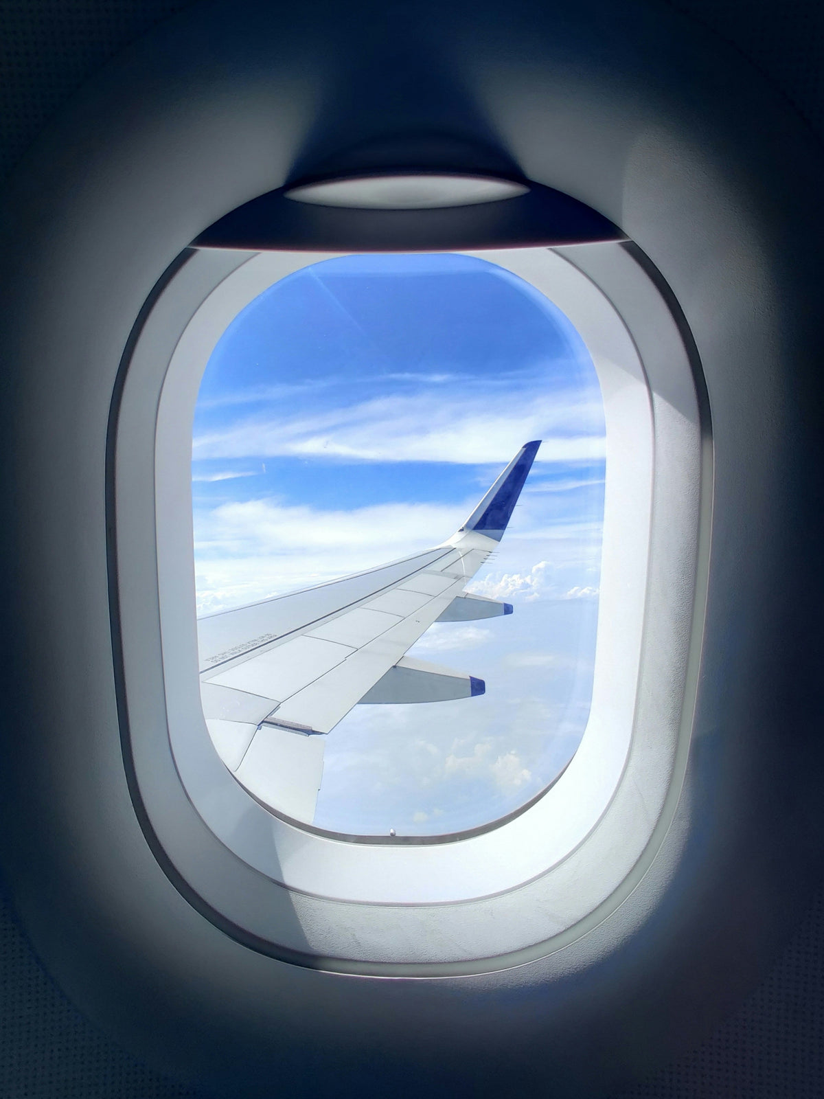 Person looking out airplane window during flight