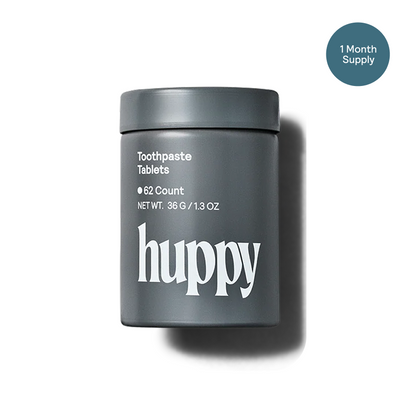Gray container of huppy charcoal mint toothpaste tablets on a white background