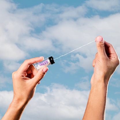 Pulling Huppy floss from the glass jar against a blue sky
