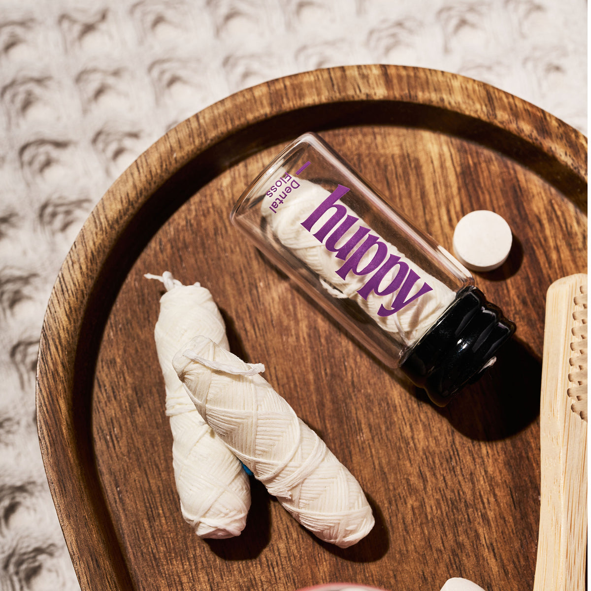 Huppy floss jar and refill spools on a wooden tray