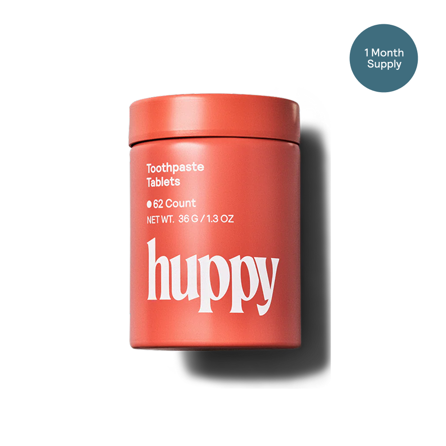 Red container of 'Huppy' toothpaste tablets on a white background